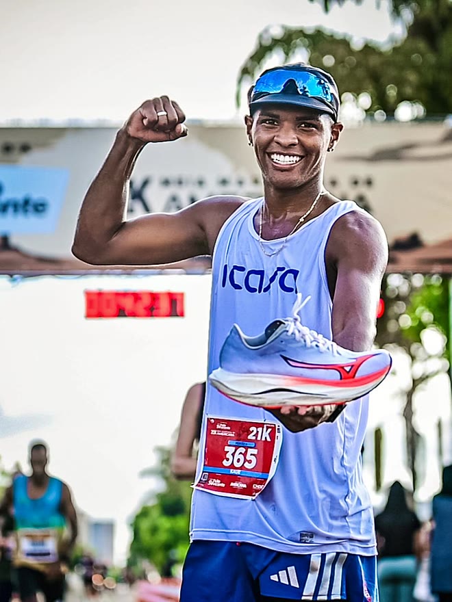 Kauê de Souza comemorando na chegada da Meia Maratona de Americana, com o tênis de prova erguido na mão
