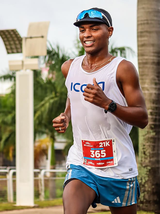 Kauê de Souza correndo e sorrindo na Meia Maratona de Americana, com o número de peito 365 na categoria 21K