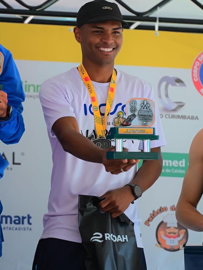 Kauê de Souza no pódio da Corrida do Bombeiro, com o troféu de terceiro colocado