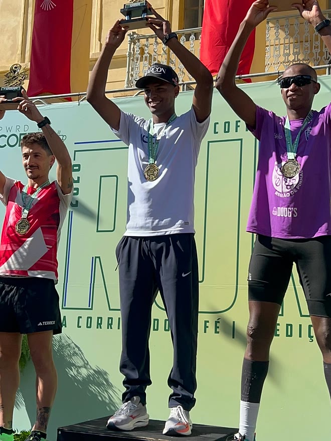 Kauê de Souza no degrau mais alto do pódio da 2ª Corrida do Café, erguendo o troféu de campeão