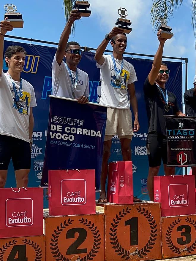 Kauê de Souza no segundo degrau do pódio da Prainha Caconde, com o troféu erguido ao lado do campeão