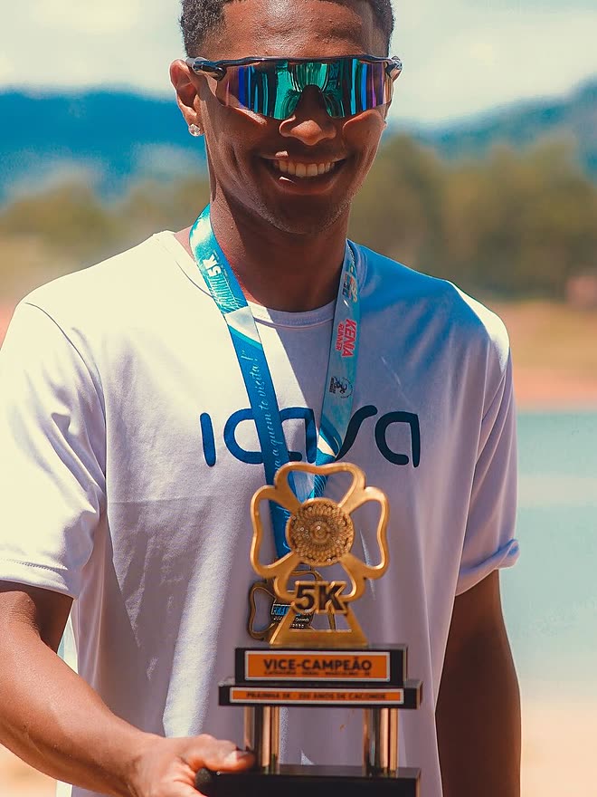 Kauê de Souza sorrindo com a medalha no pescoço e o troféu de vice-campeão dos 5 km da Prainha Caconde nas mãos