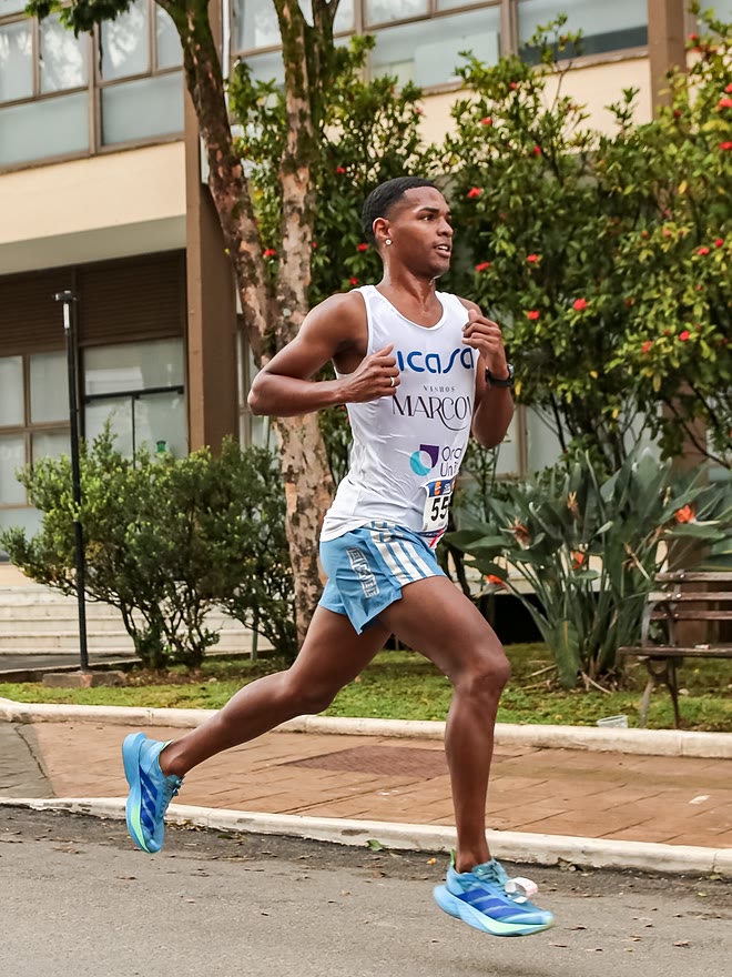 Kauê de Souza de perfil, em passada aberta no asfalto durante a 1ª Corrida Supermercados Serra Azul
