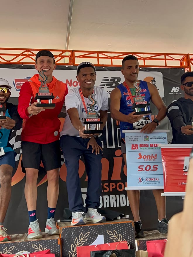 Kauê de Souza no degrau mais alto do pódio da 5ª Corrida Sônia Esportes, com o troféu de primeiro colocado