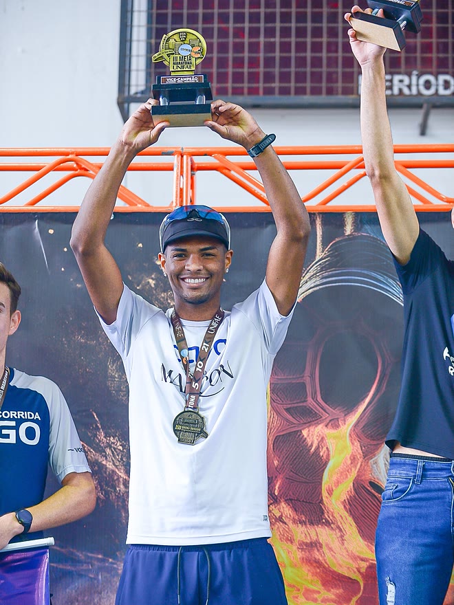 Kauê de Souza no pódio da 3ª Meia Maratona da UNIFAE, com o troféu erguido